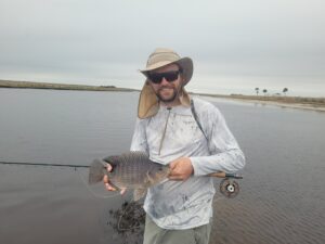 Suede holding a tilapia caught on a fly